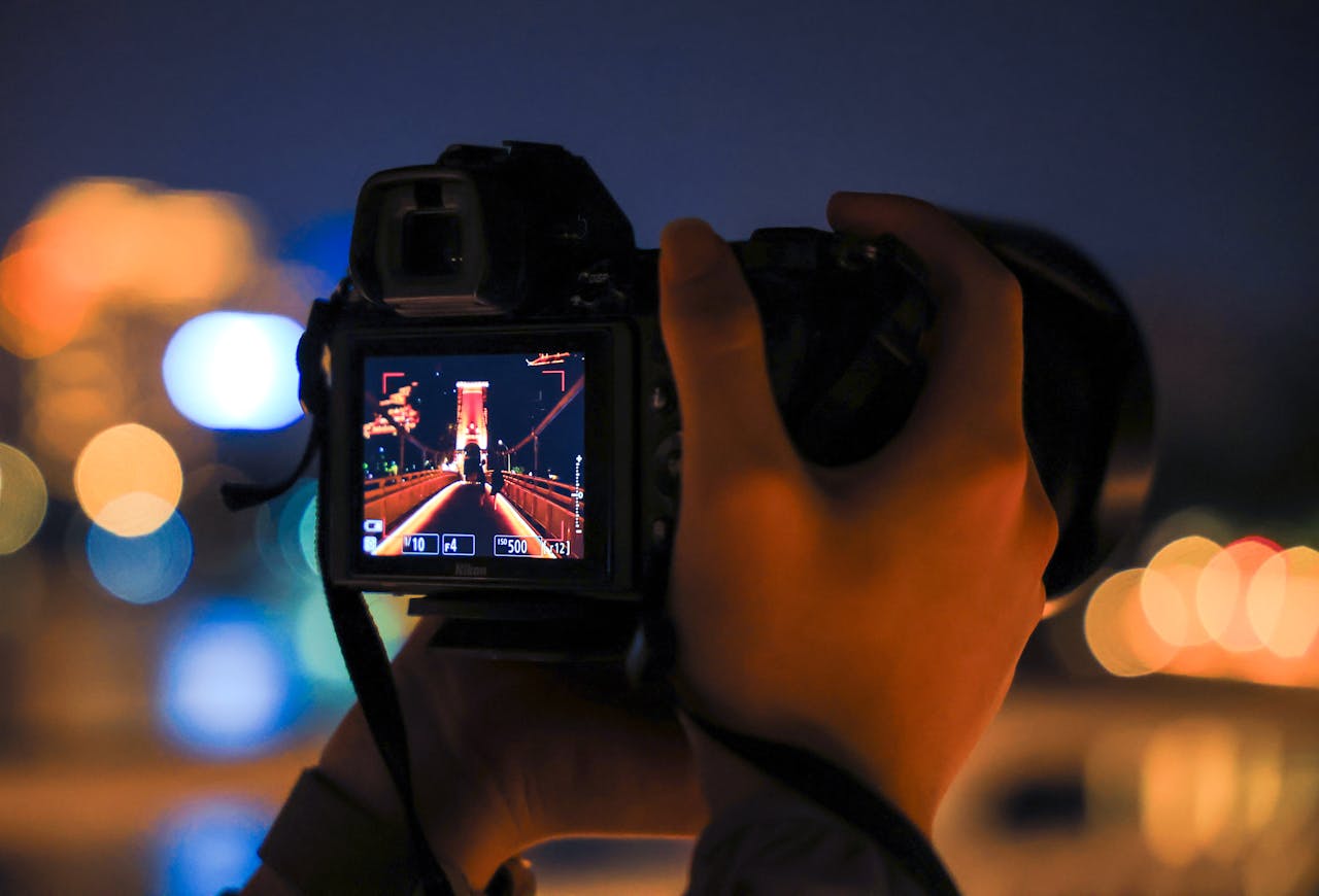 Close-up of a camera capturing a bridge at night, showcasing urban photography skills.