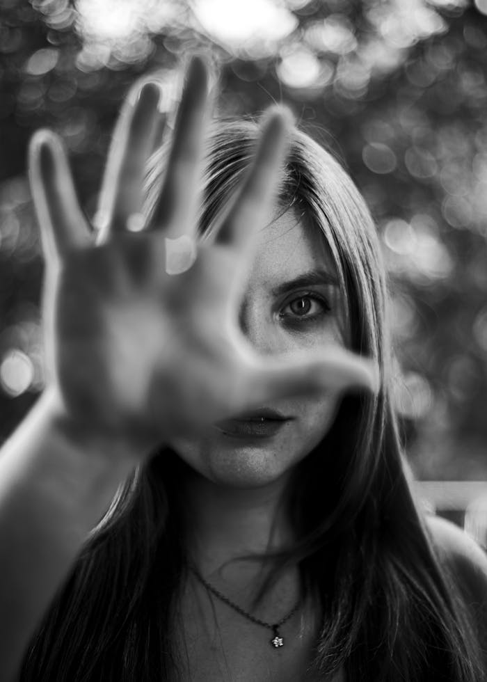Artistic black and white portrait of a young woman with outstretched hand, conveying mystery and depth.